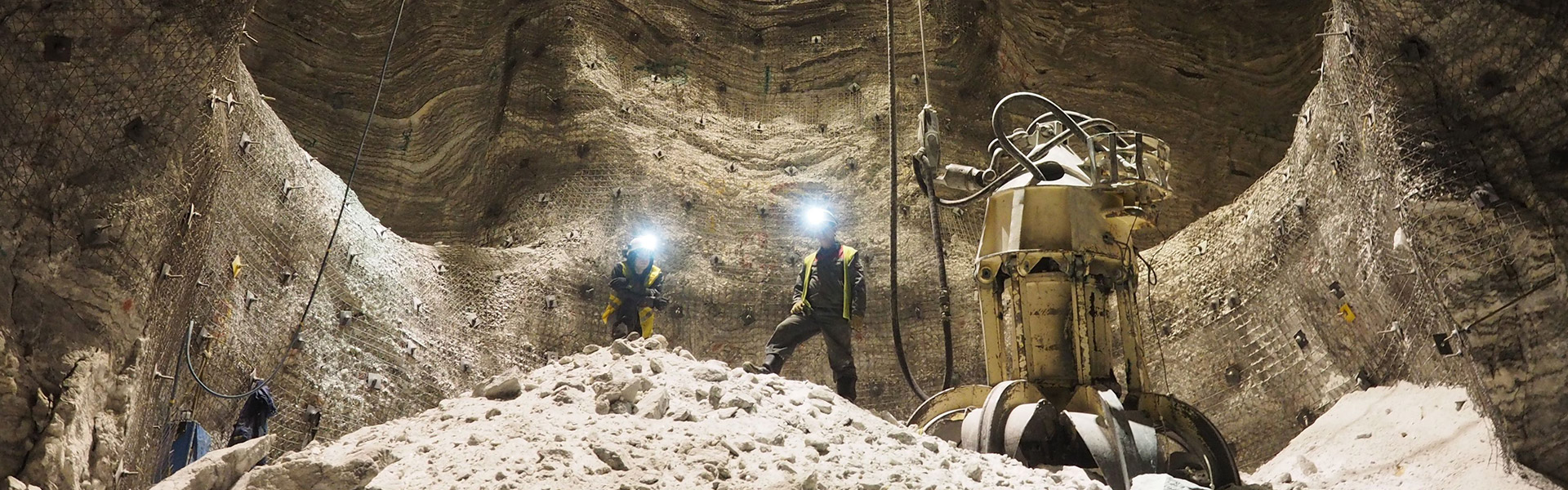 El banner del sitio web para la página de política de cookies muestra a dos empleados de Redpath de pie en lo alto de un montículo de escombros cerca de maquinaria pesada, dentro de una mina excavada.