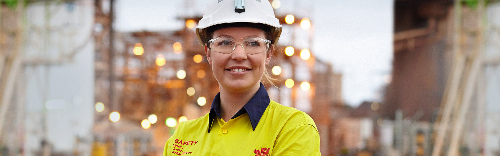 La bannière du site Web pour la page de confidentialité des données montre une jeune employée de Redpath debout devant un chantier, portant des lunettes de sécurité et un casque, souriant et regardant avec optimisme au loin.