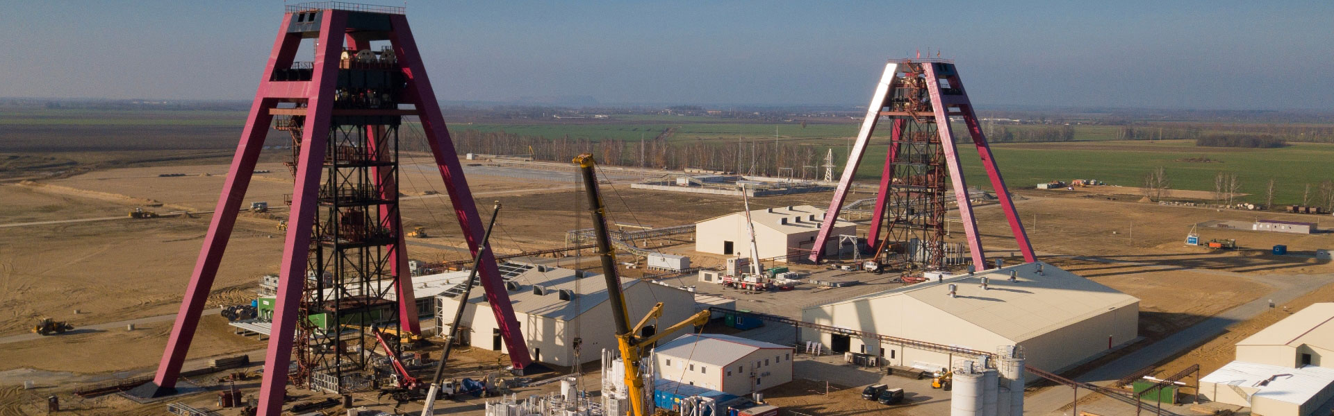 Redpath website banner for Europe page shows a mine site centered around two tall, red-framed headframes against a backdrop of flatlands and a hazy sky.