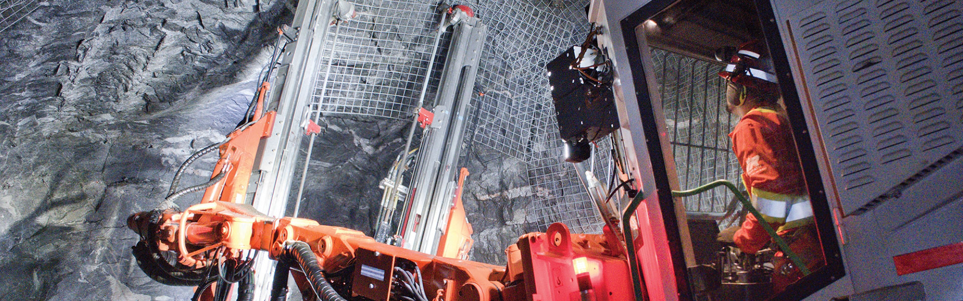 The banner for the Americas page shows a Redpath employee operating a bolt drill to apply wire meshing onto the walls and ceiling of an underground mine tunnel.