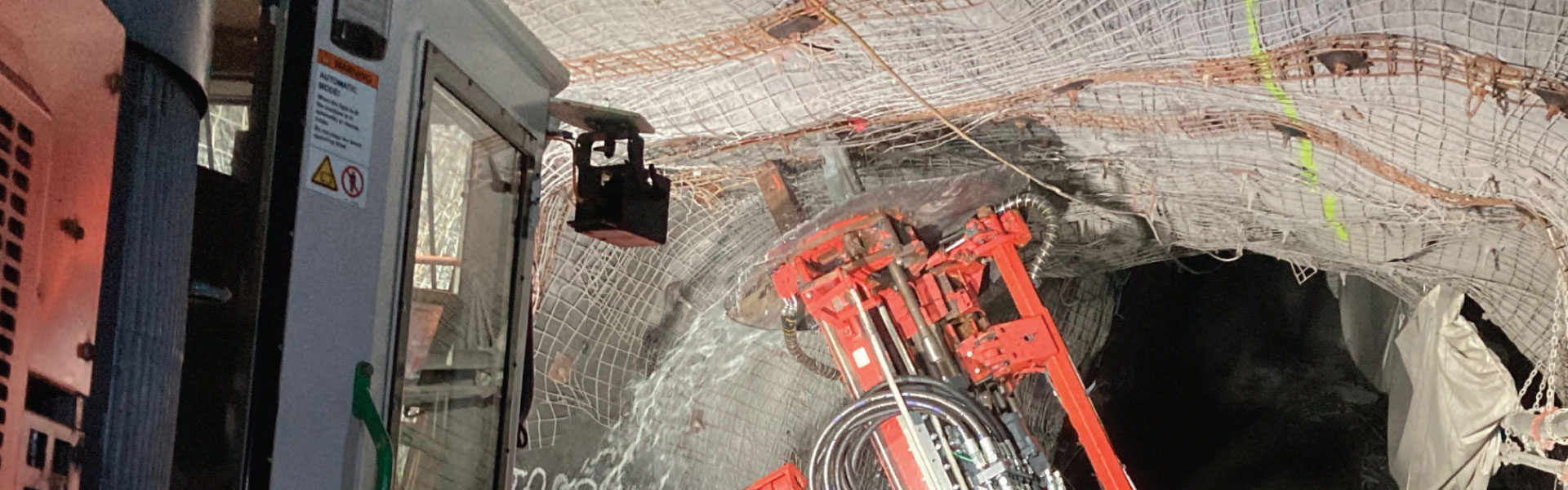 Un taladro percusivo que aplica una malla de alambre en las paredes y el techo de un túnel subterráneo para reforzar la integridad estructural.